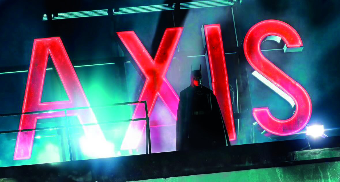 Batman standing high above the illuminated Axis Chemicals sign